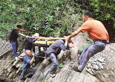 重慶市巫山縣兩坪鄉(xiāng)溪溝村長期季節(jié)性缺水，為切實解決缺水難題，村干部帶領(lǐng)群眾上山尋水。圖為2020年6月，該村干部群眾抬著百余斤重的發(fā)電機穿越陡峭的懸崖，把海拔800多米高的山泉水引到村上蓄水池。蘇耀波 攝